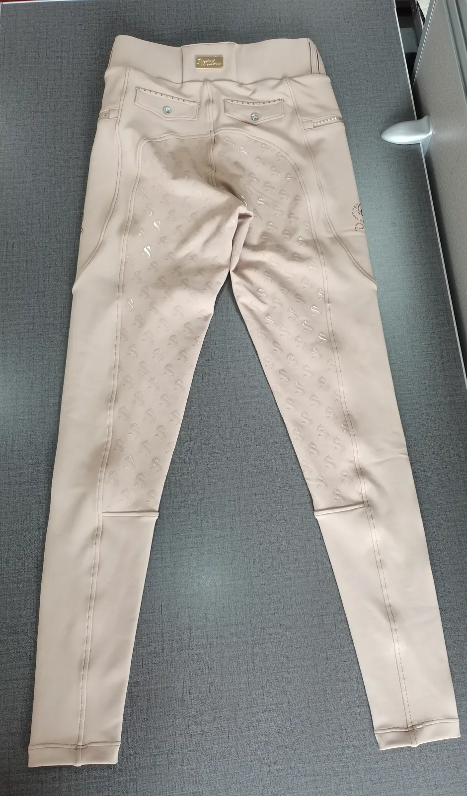Beige Reithose, Rückansicht, mit eingezeichneten Messpunkten für Bundweite, Hüftweite, Bundhöhe und Innenbeinlänge